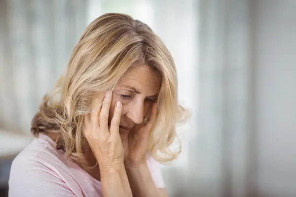 tense-senior-woman-sitting-in-bedroom